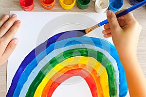 Kids painting watercolor rainbows at table at home. Arts and crafts