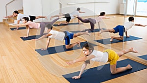 Kids and parents doing bird dog exercise in gym