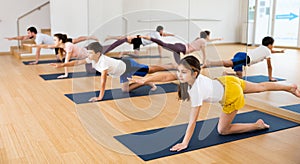 Kids and parents doing bird dog exercise in gym