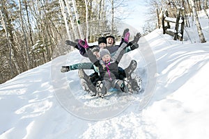 Kids with parents is sledging in winter-landscape