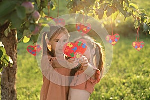 Kids in park at sunset and show heart of colored pieces puzzles on autism Day