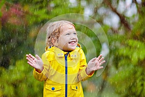 Kids play in autumn rain. Child on rainy day