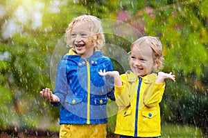 Kids play in autumn rain. Child on rainy day