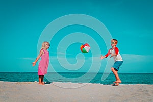 Kids play with ball on beach, boy and girl have fun at sea