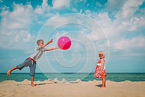 Kids play with ball on beach, boy and girl have fun at sea