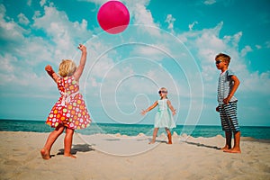 Kids play with ball on beach vacation, boy and girls have fun at sea