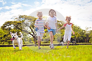 Kids play with dog. Children and puppy run in park