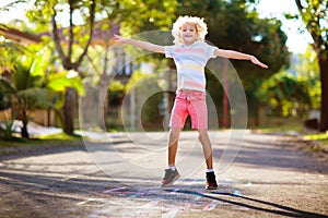 Kids play hopscotch in summer park. Outdoor game