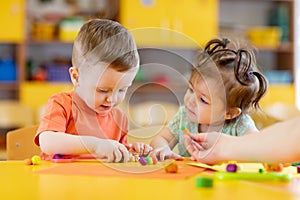 Kids play in kindergarten with interest. Children sculpt from plasticine in day care centre.