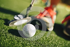 Kids play mini-golf. Close-up image of the player in snickers with a mini golf club