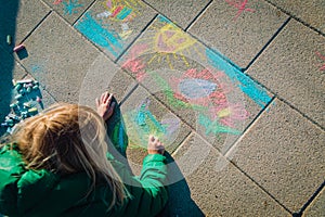 Kids play outdoors - little girl drawing pictures on asphalt