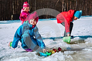 Kids play with paper boats in spring puddle