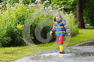 Kids play in rain and puddle in autumn