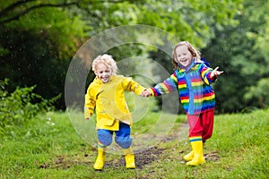 Kids play in rain and puddle in autumn