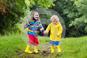 Kids play in rain and puddle in autumn