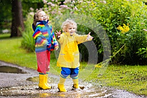 Kids play in rain and puddle in autumn