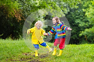 Kids play in rain and puddle in autumn