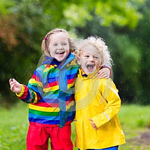 Kids play in rain and puddle in autumn