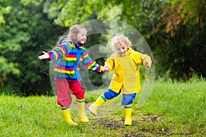 Kids play in rain and puddle in autumn