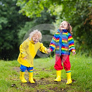 Kids play in rain and puddle in autumn