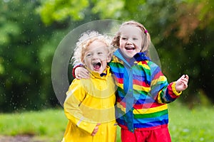 Kids play in rain and puddle in autumn