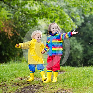 Kids play in rain and puddle in autumn