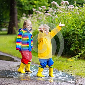 Kids play in rain and puddle in autumn