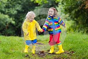 Kids play in rain and puddle in autumn