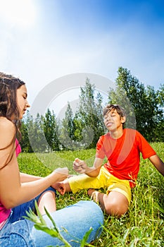 Kids play rock-paper-scissors on grass