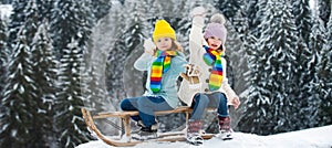 Kids play snowball, snow ball fight for children. Happy little kids wearing knitted hat, scarf and sweater play with