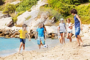 Kids play soccer ball on the sea beach