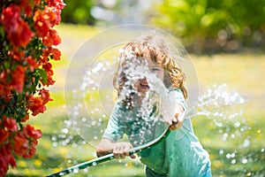 Kids play with water garden hose in yard. Outdoor children summer fun. Little boy playing with water hose in backyard