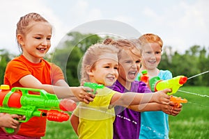 Kids play with water guns on a meadow