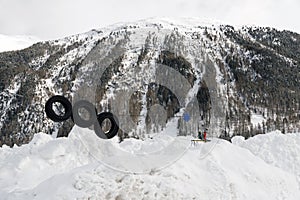 A kids playground under snow and snowy mountains and a small town in the alps switzerland