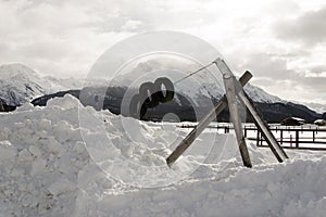 A kids playground under snow and snowy mountains and a small town in the alps switzerland