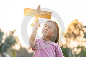 The kids playing the airplane toy in the park during sunrise.