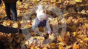 Kids playing in autumn park. A little girl lies in a pile of yellow leaves, leaves pour down on top of her, joy