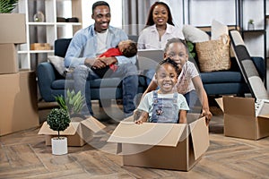 Kids playing with boxes while parents relaxing on sofa