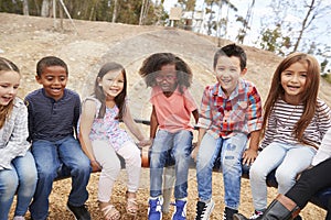 Kids playing on a carousel in schoolyard looking to camera