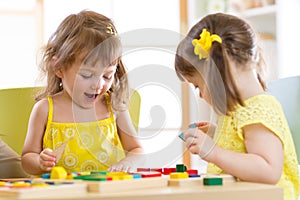 Kids playing with colorful block toys. Two children girls at home or daycare center. Educational child toys for preschool and kind