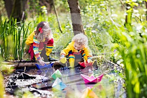 Kids playing with colorful paper boats in a park