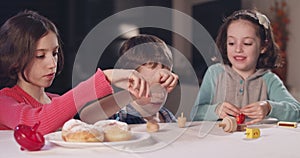 Kids playing with dreidels during Hanukka at home