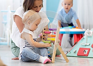 Kids playing on floor with educational toys in kindergarten. Children have fun in nursery or daycare. Babies with photo