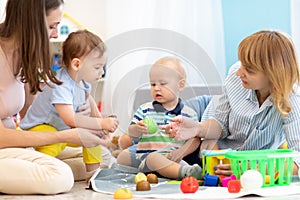 Kids playing on floor with educational toys. Toys for preschool and kindergarten. Children in nursery or daycare. Babies