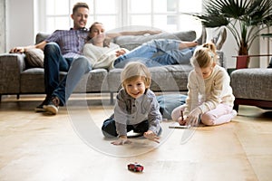 Kids playing on floor, parents relaxing on sofa at home photo