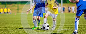 Kids playing football soccer game on sports field. Boys kicking