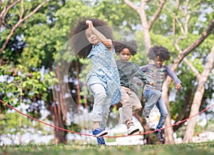 Kids playing jump over the rope in the park on sunny summer day.