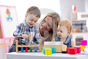 Kids playing with mother at table with educational toys. Toys for preschool and kindergarten. Children in nursery or