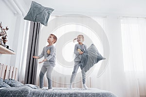 Kids playing in parents bed. Children wake up in sunny white bedroom. Boy and girl play in matching pajamas. Sleepwear
