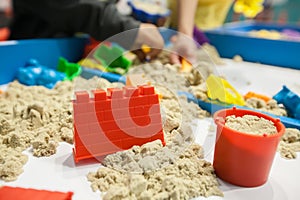 Kids playing plastic mold toys with sand on sandbox.